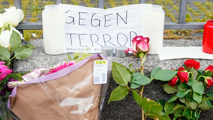 Kerzen, Blumen und ein Blatt Papier mit der Aufschrift "Gegen Terror" stehen am Tatort auf dem Marktplatz in Mannheim. 