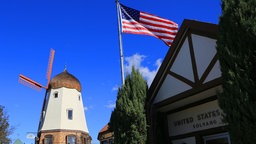 Windmühle, US-Flagge und Hausfront in Solvang, Santa Barbara County, Kalifornien.