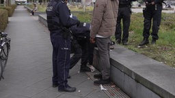 Zwei Polizisten kontrollieren einen Passanten