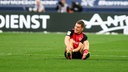 Florian Wirtz von Bayer 04 Leverkusen sitzt im Spiel gegen Werder Bremen verletzt auf dem Rasen.