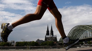 Ein Jogger in Köln mit dem Dom im Hintergrund