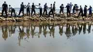 Bei Bitterfeld verlegen Menschen am 16.08.2002 Sandsäcke gegen Hochwasser