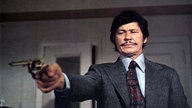 Charles Bronson hält eine Pistole in der Hand