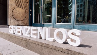 Foto von weißen Buchstaben "grenzelos" auf Treppe positioniert. 