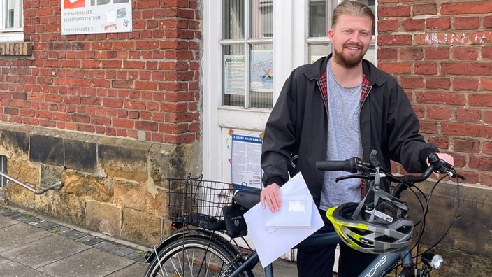 Philipp Schniederkötter mit Fahrrad und Briefumschlägen