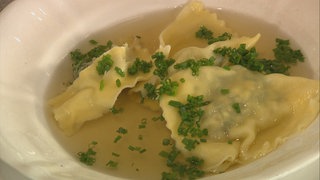 Maultaschen in Brühe und mit Schnittlauch bestreut in einem Teller