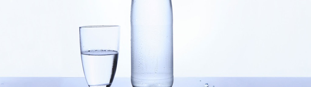 Das Bild zeigt eine Flasche Mineralwasser und ein Glas Wasser.