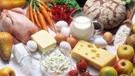 Grundnahrungsmittel wie Milch, Brot, Eier, Käse, Obst und Gemüse auf einem Tisch