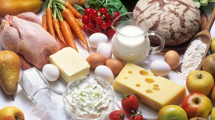 Grundnahrungsmittel wie Milch, Brot, Eier, Käse, Obst und Gemüse auf einem Tisch