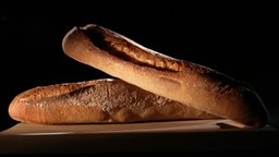 Das Bild zeigt zwei Aufbackbaguettes auf schwarzem Hintergrund.