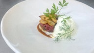 Das Bild zeigt das Gericht "Rindertartar mit Schaum und Chips vom Knoblauch".