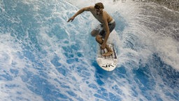 Ein Surfer springt auf einer künstlichen Surfwelle in der Indoor- Surfhalle.