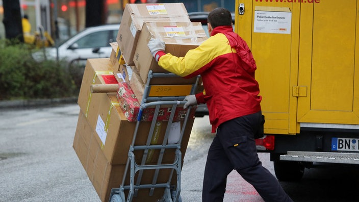 Ein Paketzusteller mit einer Sackkarre und Paketen.