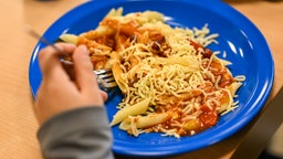 Ein Kind hat beim Schulessen Chilli sin Carne auf dem Teller.