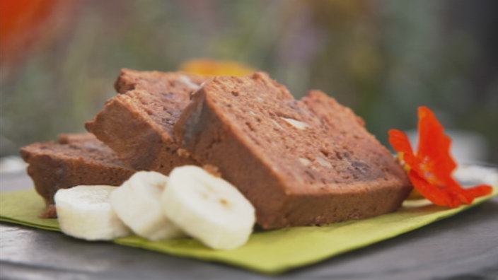 Drei Scheiben Bananenbrot liegen mit drei Bananenstücken auf einem Teller