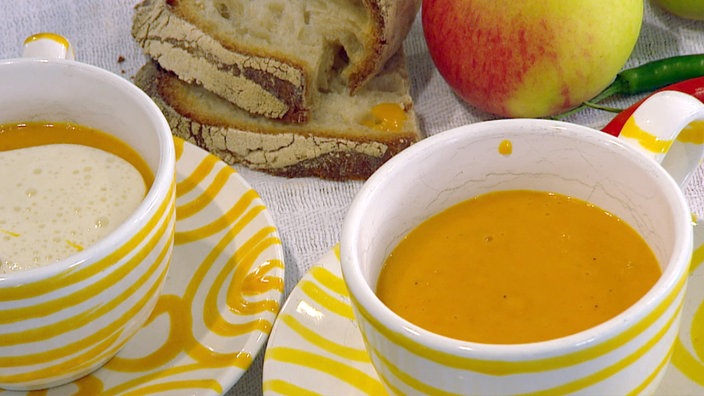 Kürbiscremesuppe in einer Suppentasse, daneben ein Apfel.