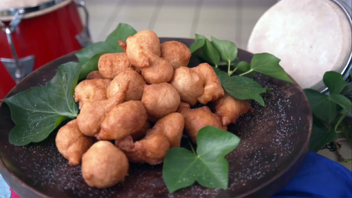 Mehrere Beignets liegen aufgestapelt auf einem mit Blättern verzierten Teller.