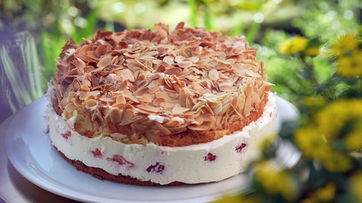 Eine aufgeschichtete Creme-Mandeltorte mit Früchten.