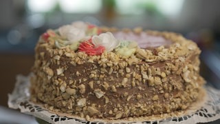 Die Kiewer Torte wird auf einer Platte serviert und ist mit Dekorblüten verziert.