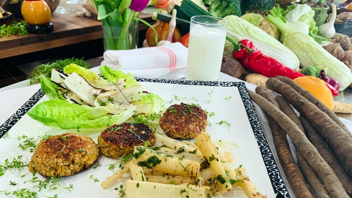 Fleischlose Frikadellen mit Salat und Beilagen auf einem Teller angerichtet