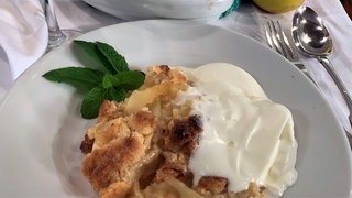 Portion Apfelstreusel mit Sahne auf einem Teller 