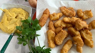 Gebackene Kibbeling auf einem Küchenpapier, daneben in einer Schale Curry-Mayonnaise