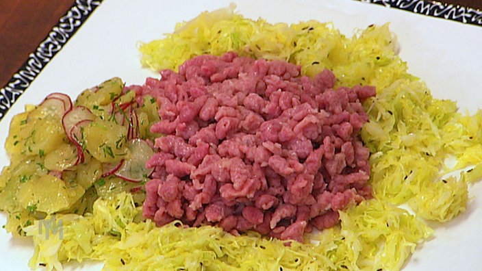 Rote-Bete-Spätzle auf einem Teller mit Kraut angerichtet