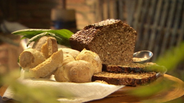 Schwarzbrot und Karotten-Dinkel-Brötchen auf einem Teller präsentiert. 