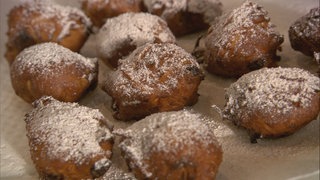 Mehrere mit Puderzucker bestreute Apfel-Püfferkes auf einem Blech