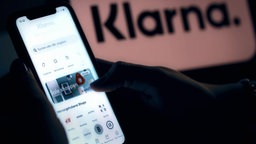 das Bild zeigt ein Handy und die App Klarna