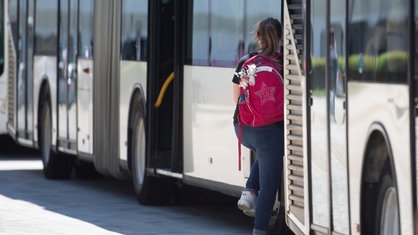 Ein Mädchen steigt in einen Schulbus ein