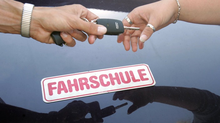 Fahrlehrer gibt der Fahrschülerin den Autoschlüssel