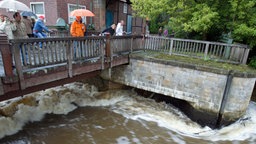 Passanten stehen im August auf einer Brücke der Vechte und schauen auf die reißende Strömung, 2010